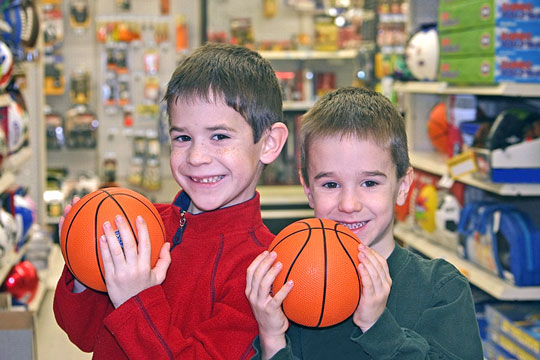 two boys holding basketballs in a sporting goods store